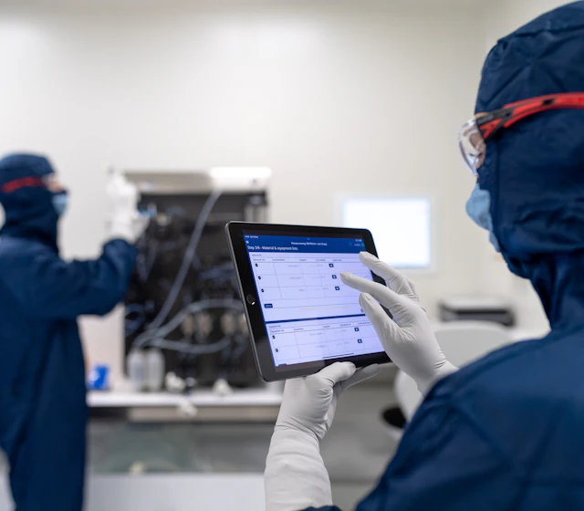 Technicien en tenue de salle blanche consultant une tablette