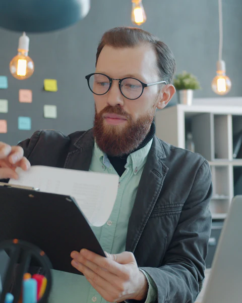 Homme à lunettes examinant des documents à son bureau